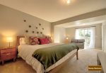 Ground level master suite with carpeted floors, king bed, modern decor, and a flat-screen HDTV